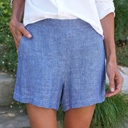 Person wearing blue shorts and a white shirt with a blurred natural background