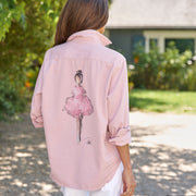Person wearing a pink shirt with a graphic of a ballerina outdoors.