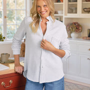 Woman wearing a gray shirt and blue jeans standing in a kitchen.