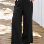 Person wearing black wide-leg pants on a wooden deck