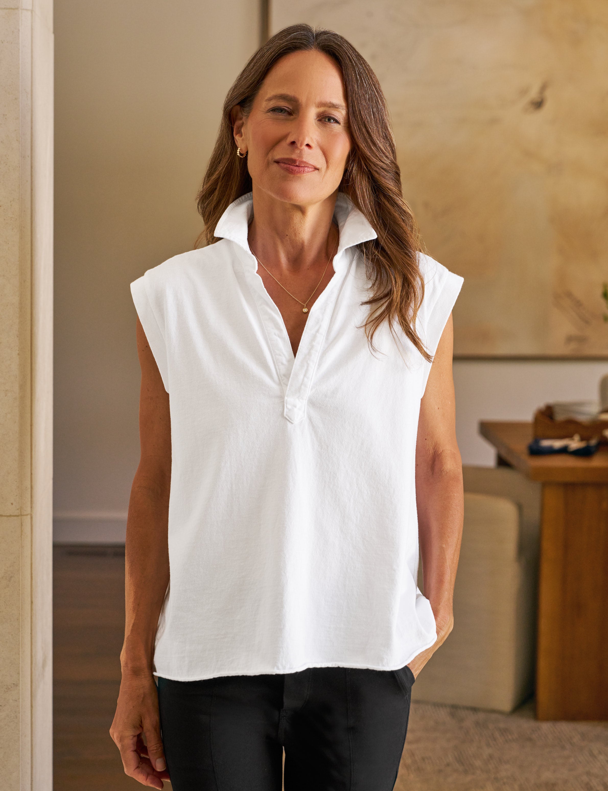 Woman wearing a white sleeveless blouse in an indoor setting