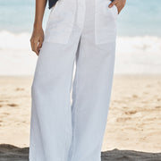Person wearing white pants standing on a beach with a blurred background