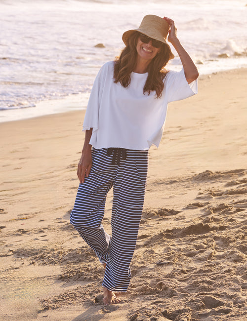 Woman in white top and striped pants on a beach, view 5