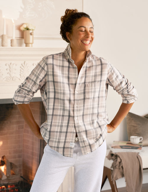 Woman wearing a plaid shirt in a cozy living room with a fireplace., front view