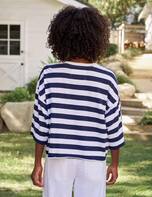 Person wearing a navy and white striped shirt in an outdoor setting, alternate view