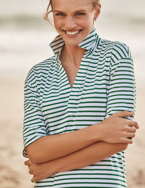 Woman wearing a green and white striped dress on a beach., view 4