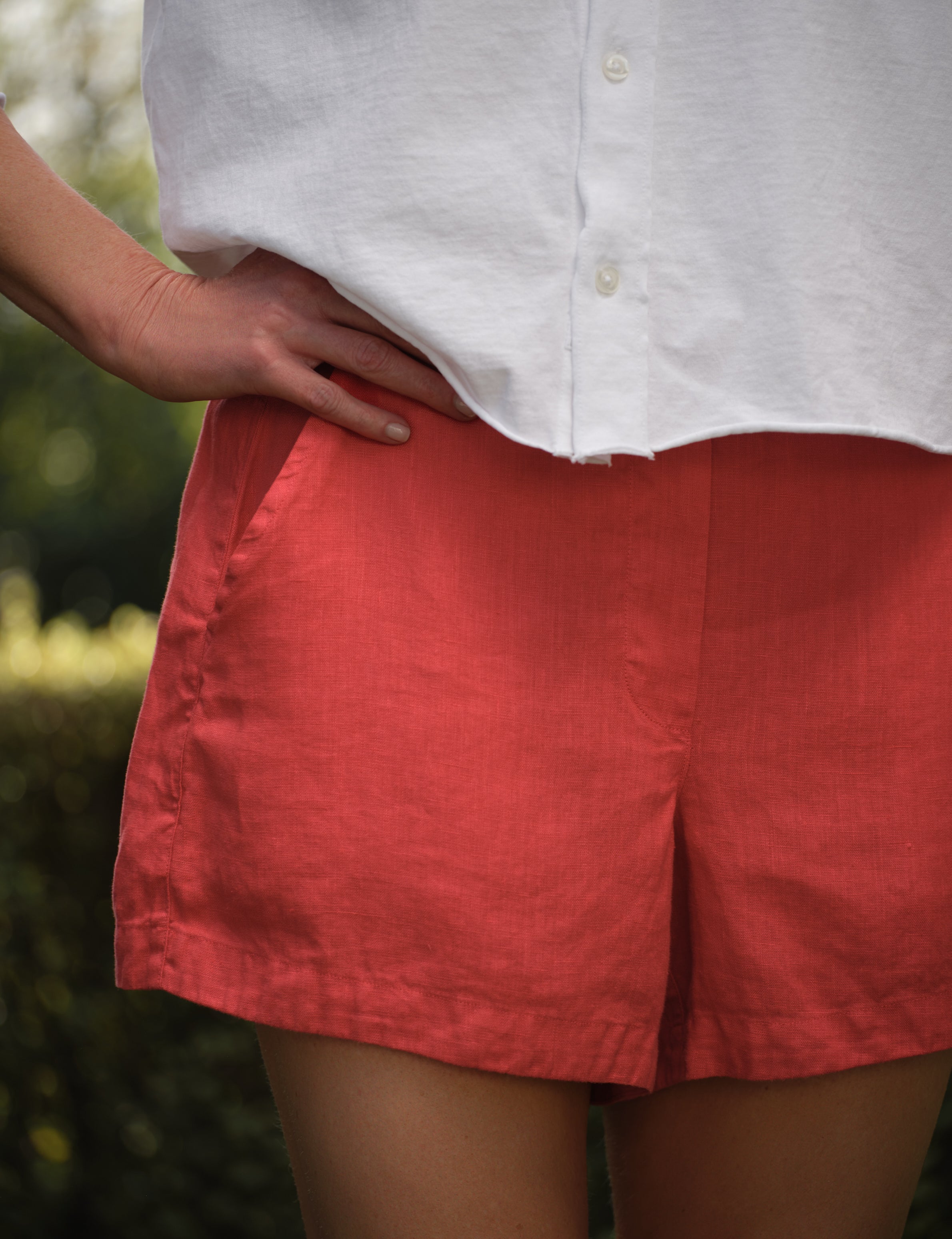Person wearing a white shirt and red shorts with a blurred background, view 3
