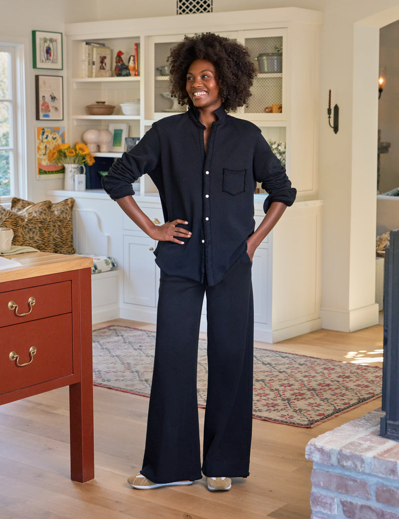 Woman in a navy outfit standing in a living room with a red dresser and white shelves.