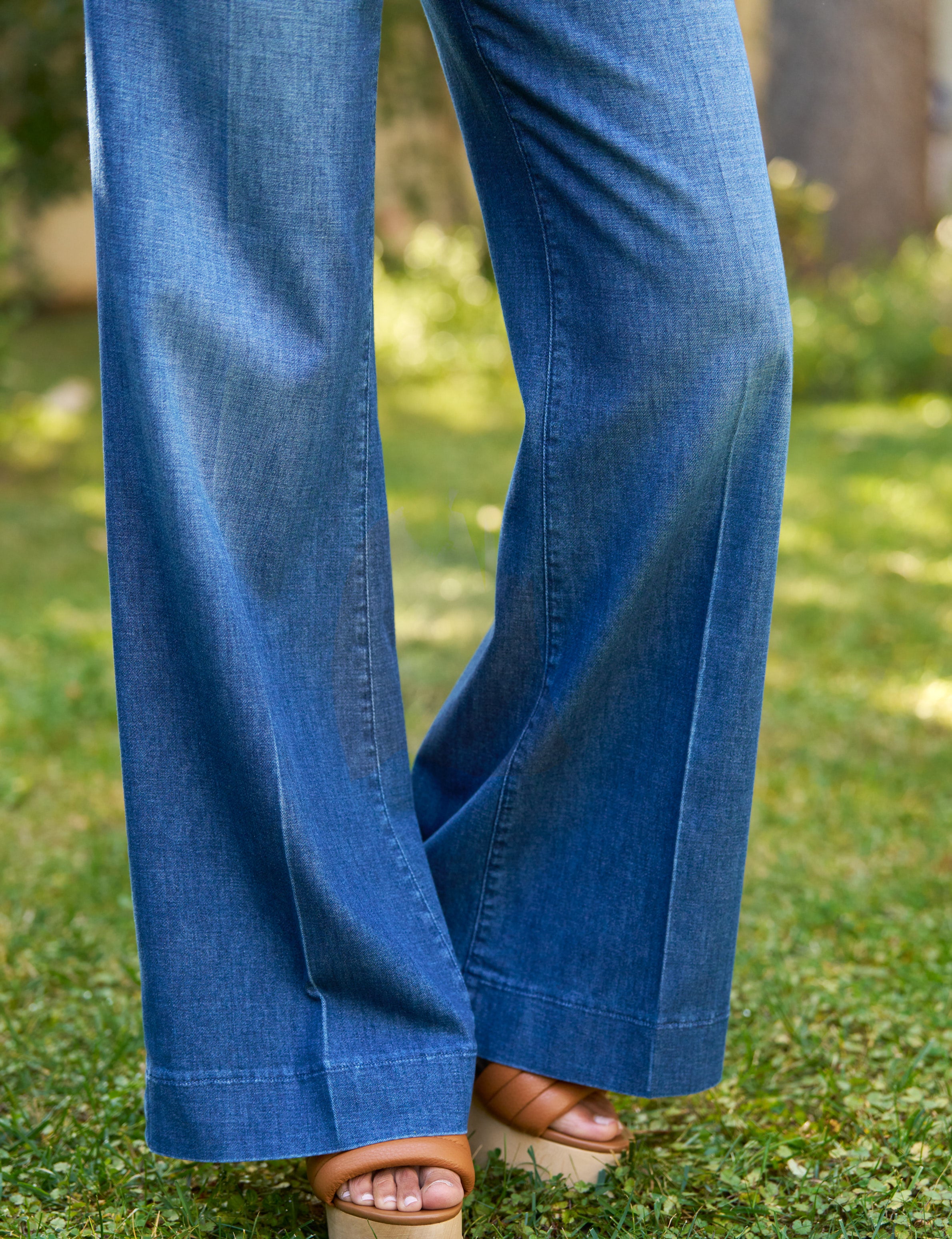 Blue jeans being worn on a grassy background, view 3