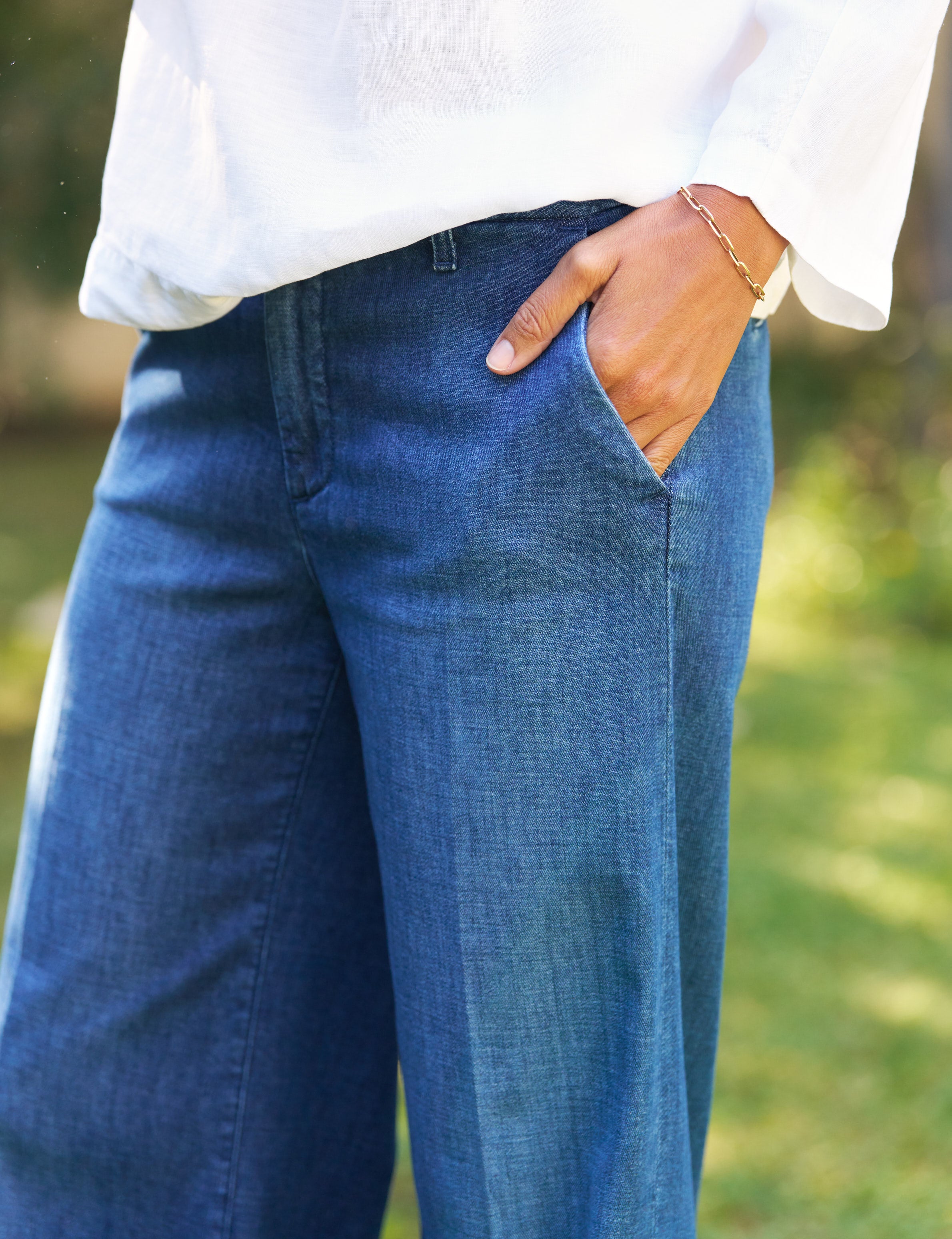 Person wearing blue jeans with a blurred natural background, alternate view