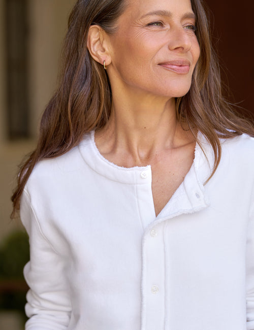 A close-up shot of a woman wearing a white cardigan, set against a softly blurred background., view 3