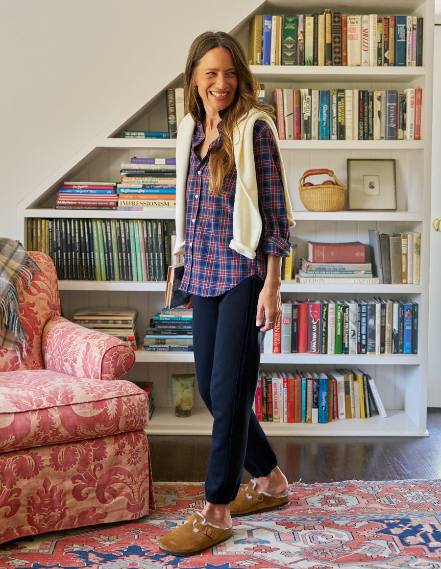 Woman standing in a room with a bookshelf and pink chair