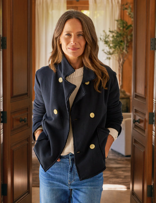 Woman wearing a navy blue coat with gold buttons in an indoor setting., front view