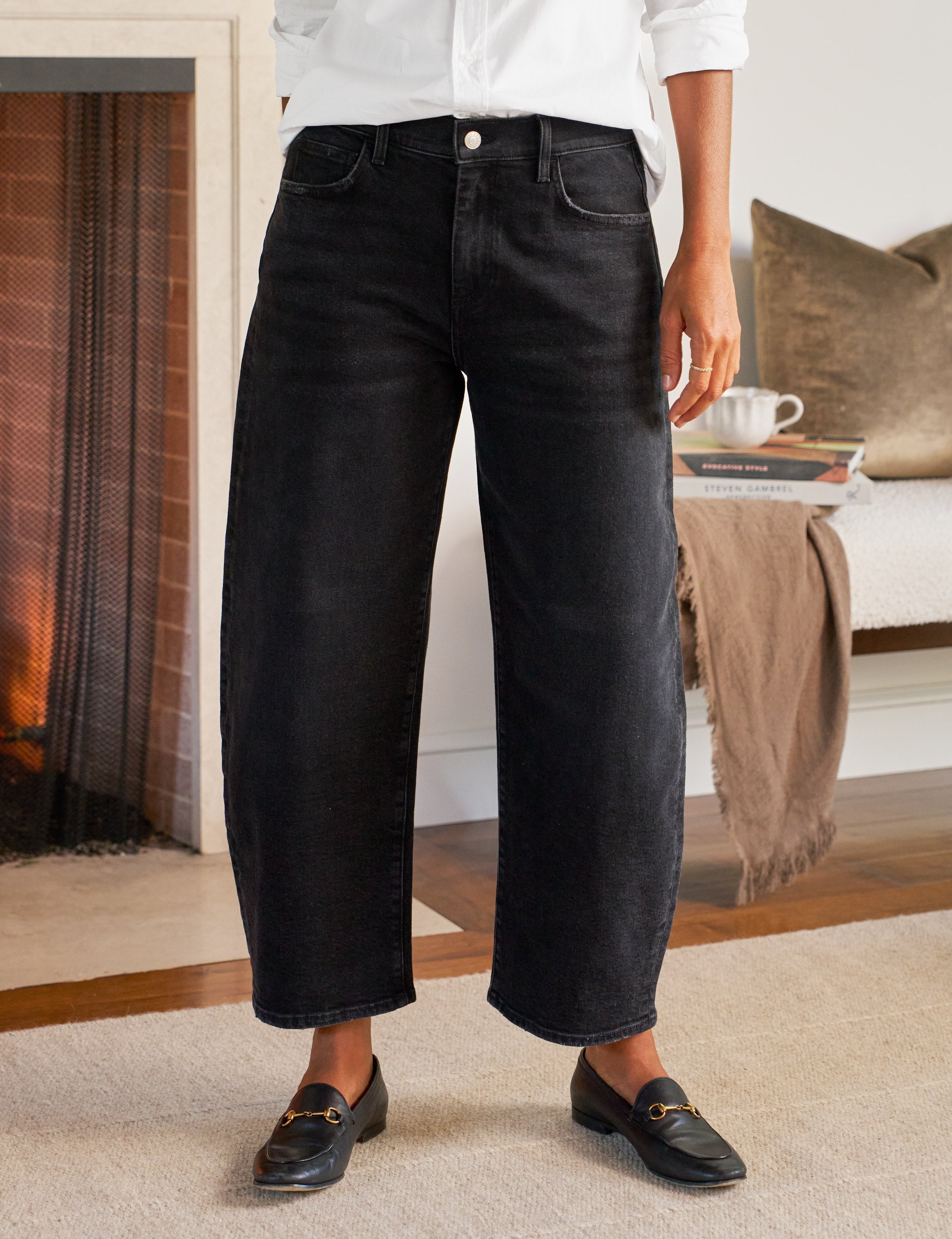 Person wearing black jeans and black shoes in a cozy living room.