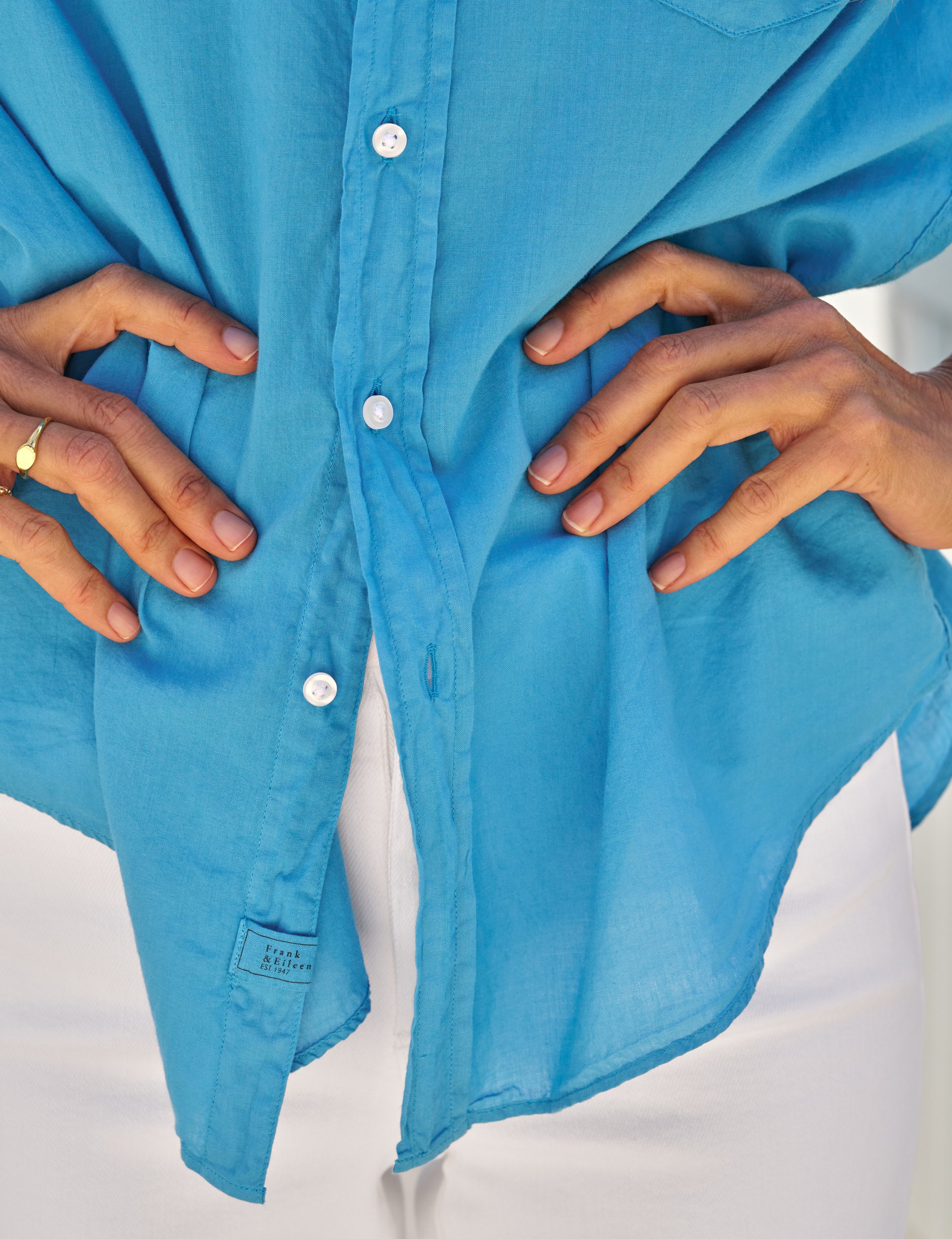Close-up of a blue shirt with hands adjusting it on a white background, view 3