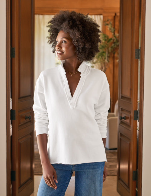 Woman wearing a white blouse and blue jeans standing in a room with wooden doors., front view
