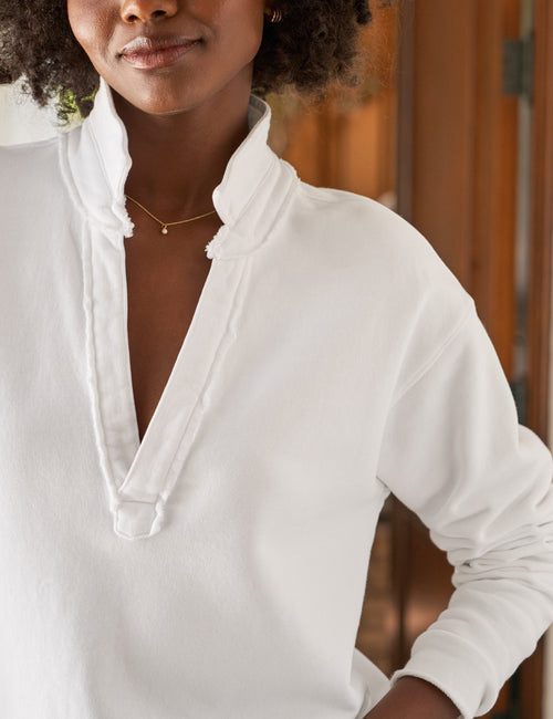 Woman wearing a white long-sleeve top with a high neckline, standing outdoors., view 3
