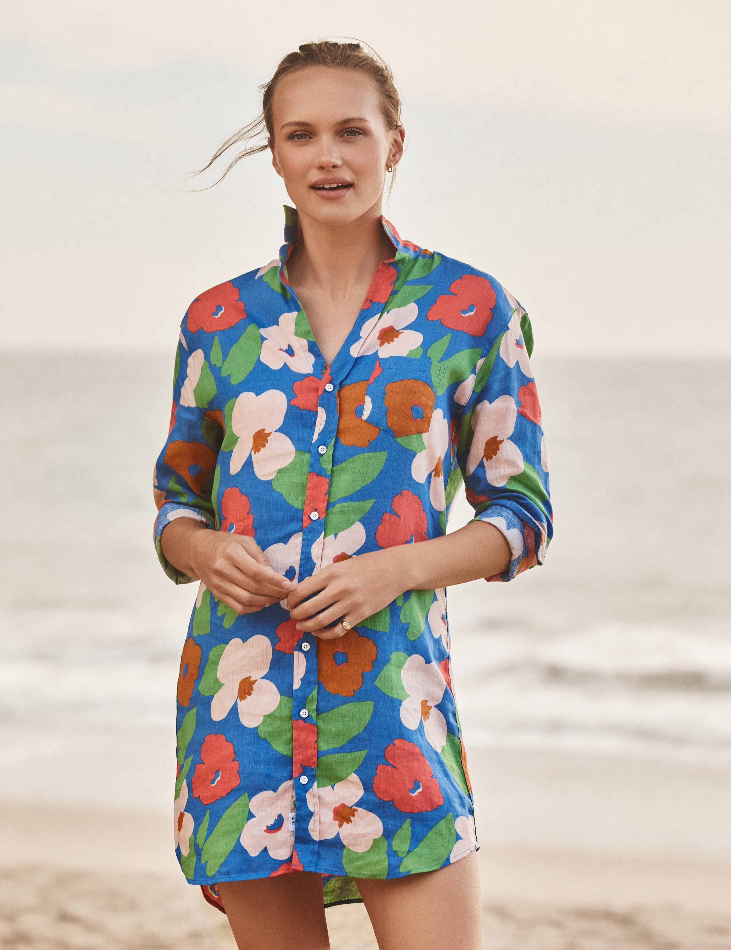 Woman wearing a colorful floral dress on a beach, front view