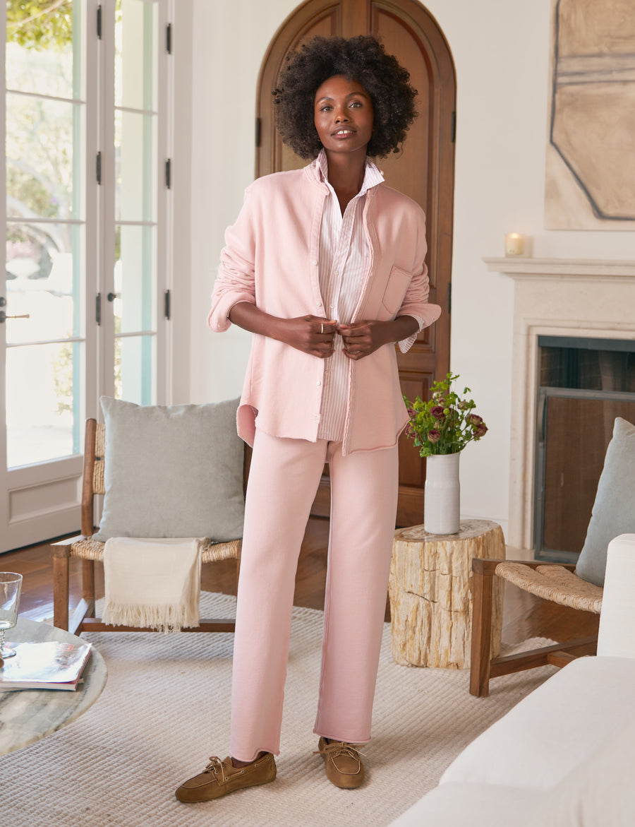 Woman in a pink outfit standing in a living room.