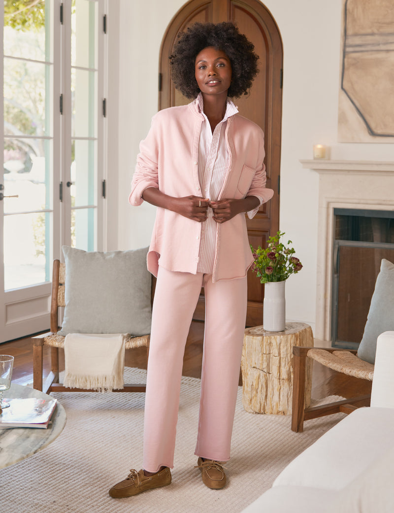 Woman in a pink outfit standing in a living room.
