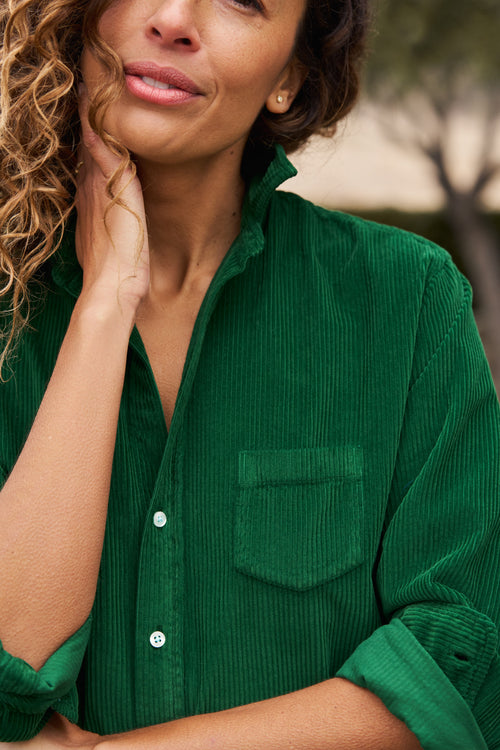 Woman wearing a green corduroy shirt with a blurred background, alternate view
