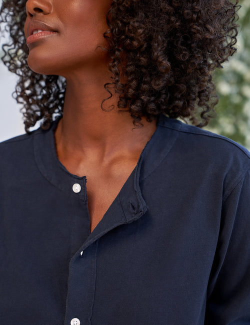 Person wearing a navy blue shirt with a blurred background, view 3