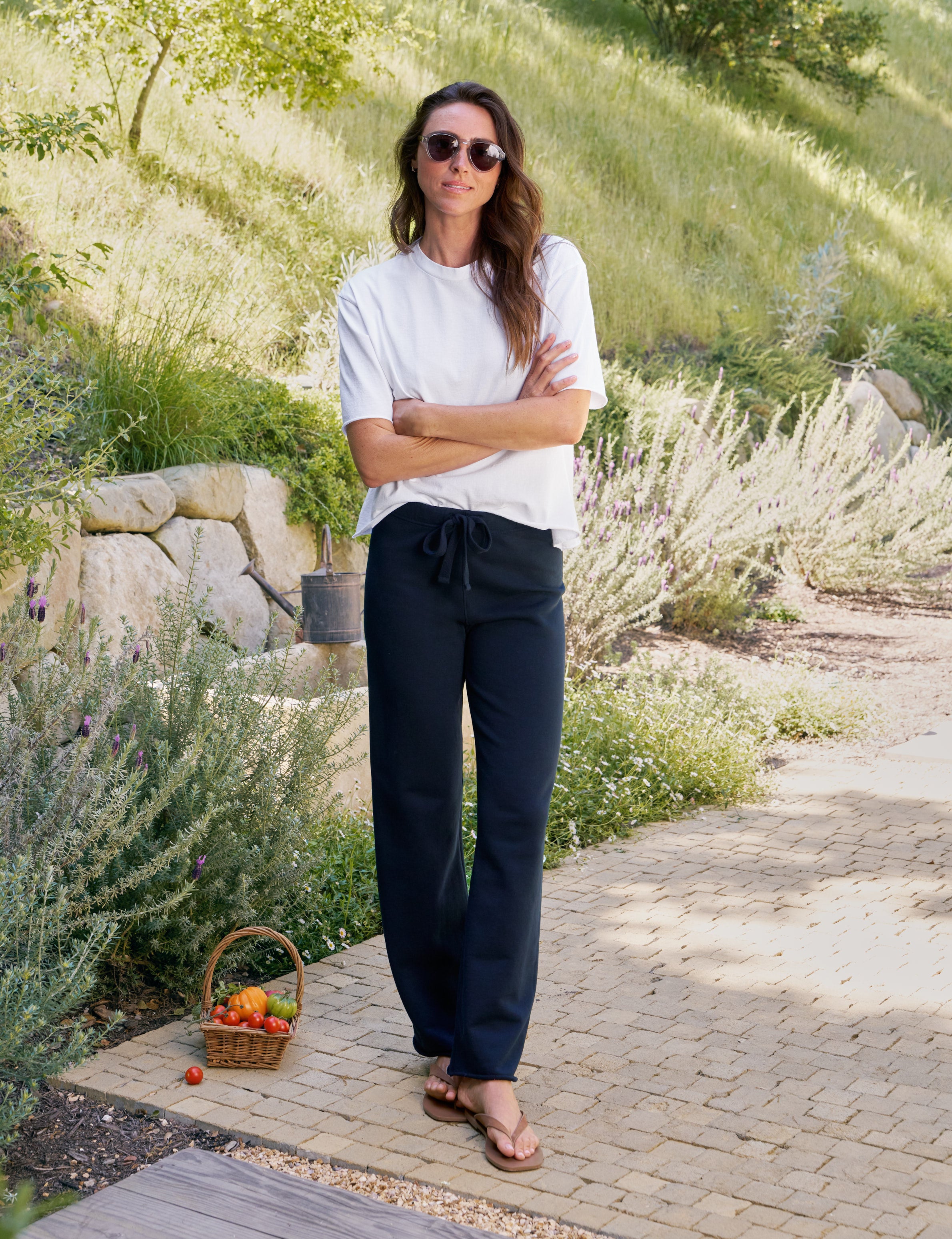Woman standing outdoors with a basket of fruit on a stone path