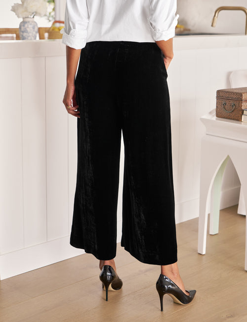 Person wearing black wide-leg pants and white shirt in a kitchen setting, alternate view
