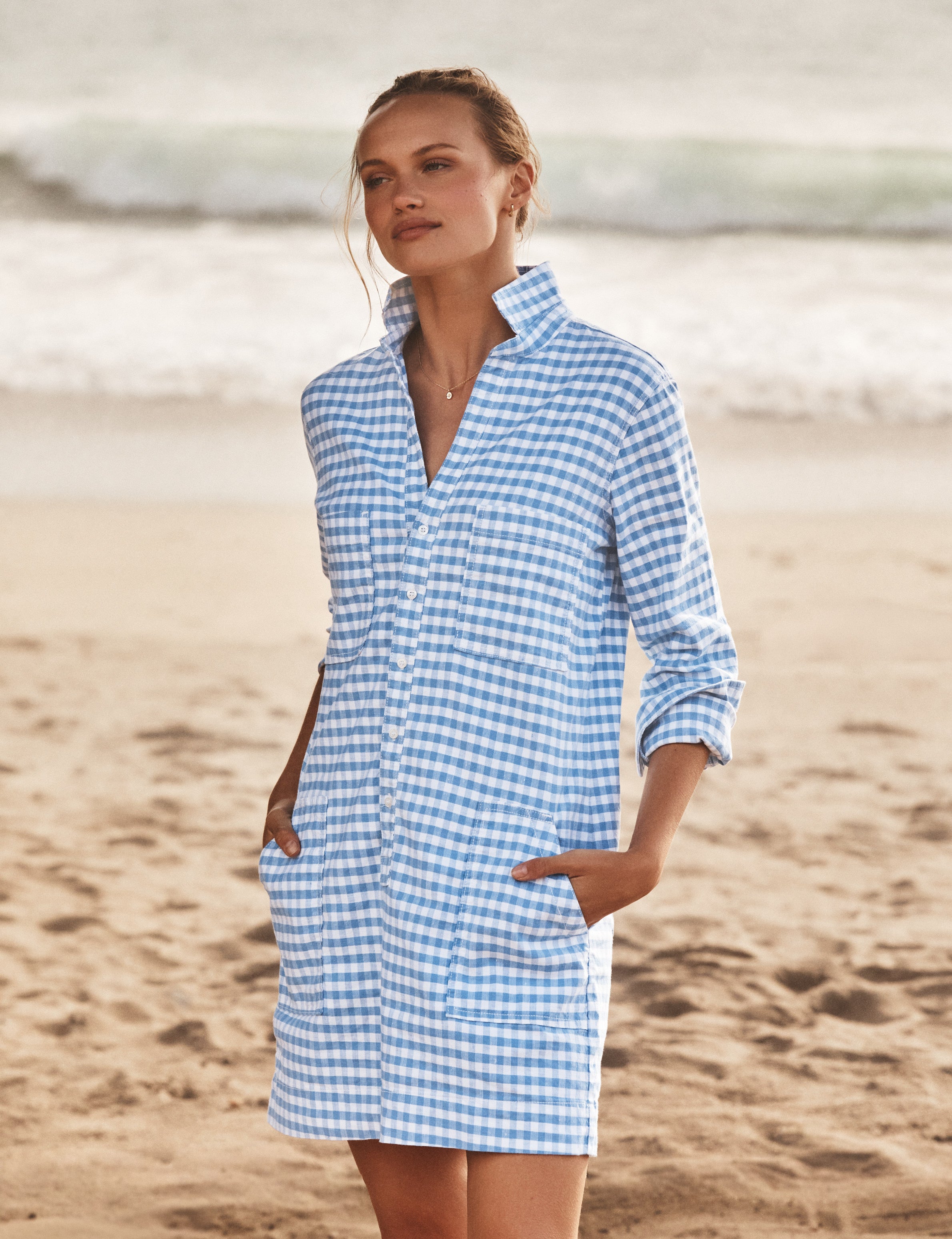 Woman wearing a blue and white checkered dress on a beach., front view