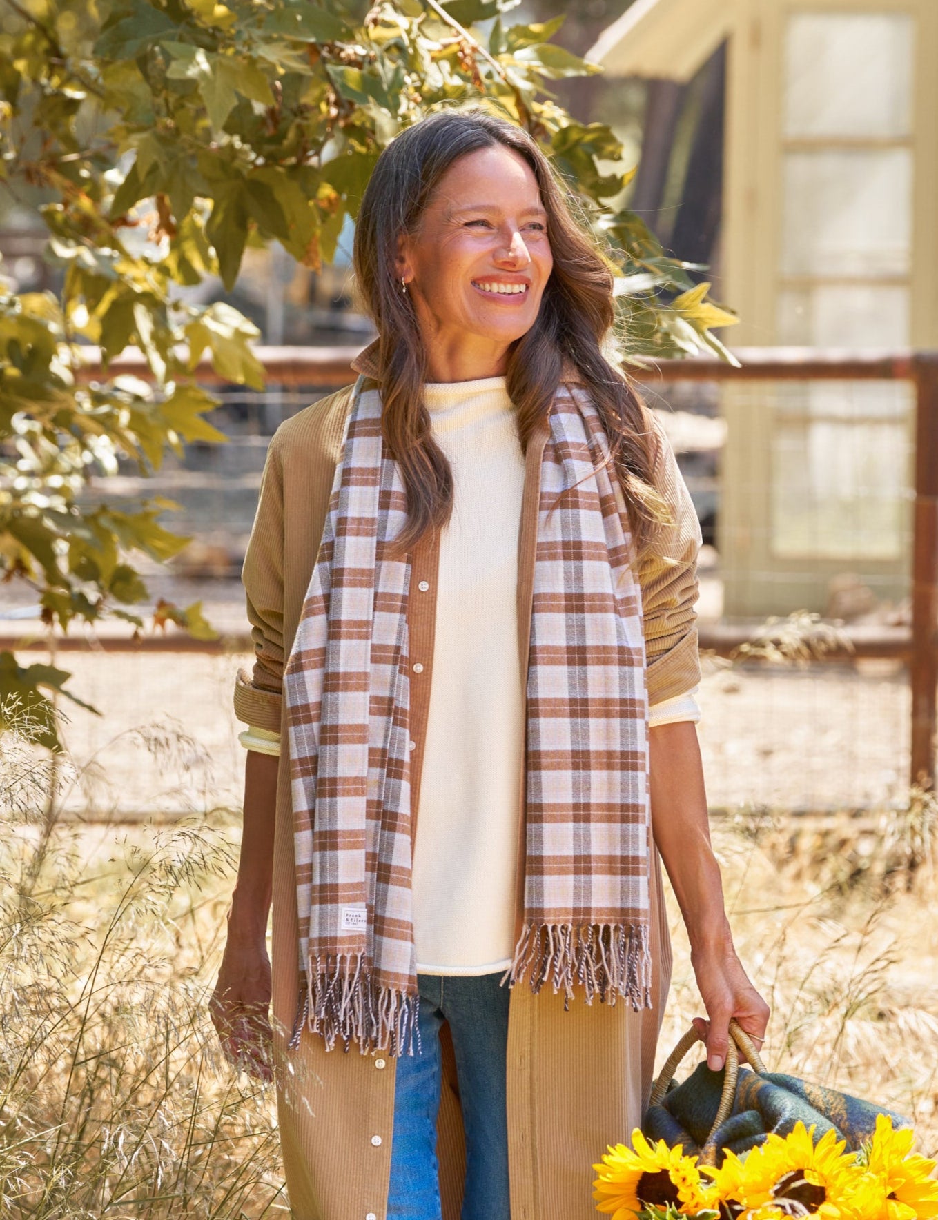 Woman holding sunflowers in a field with a building in the background