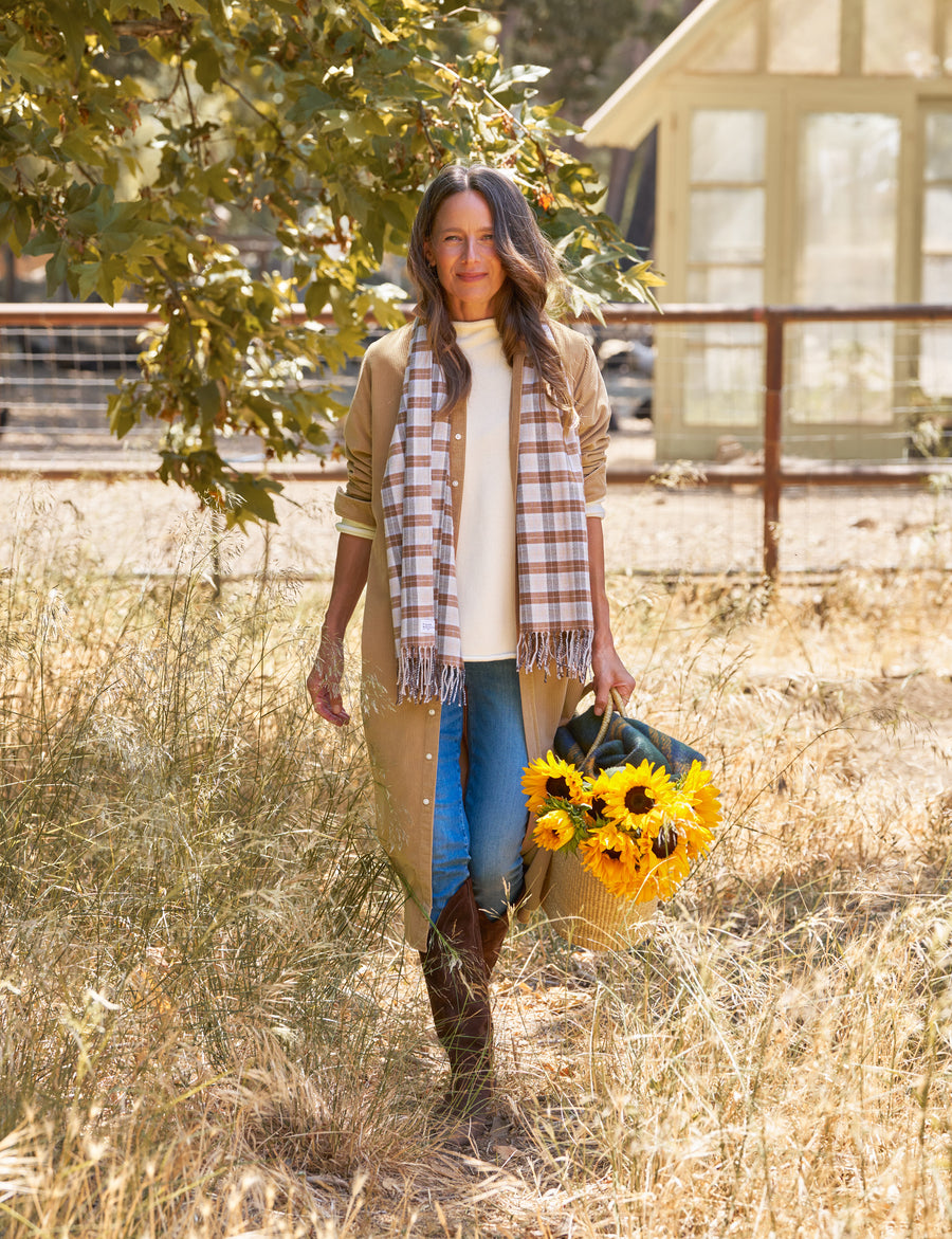 Woman holding sunflowers in a field with a house in the background