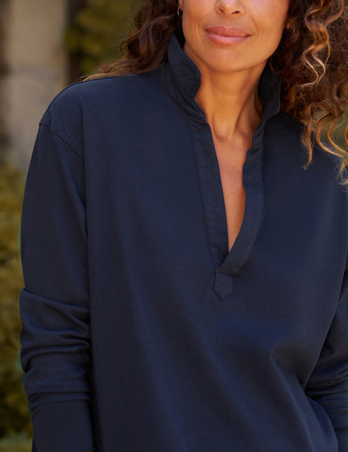 A close-up of a woman wearing a dark navy blue long-sleeve top with a high mock neck and split button placket., view 3