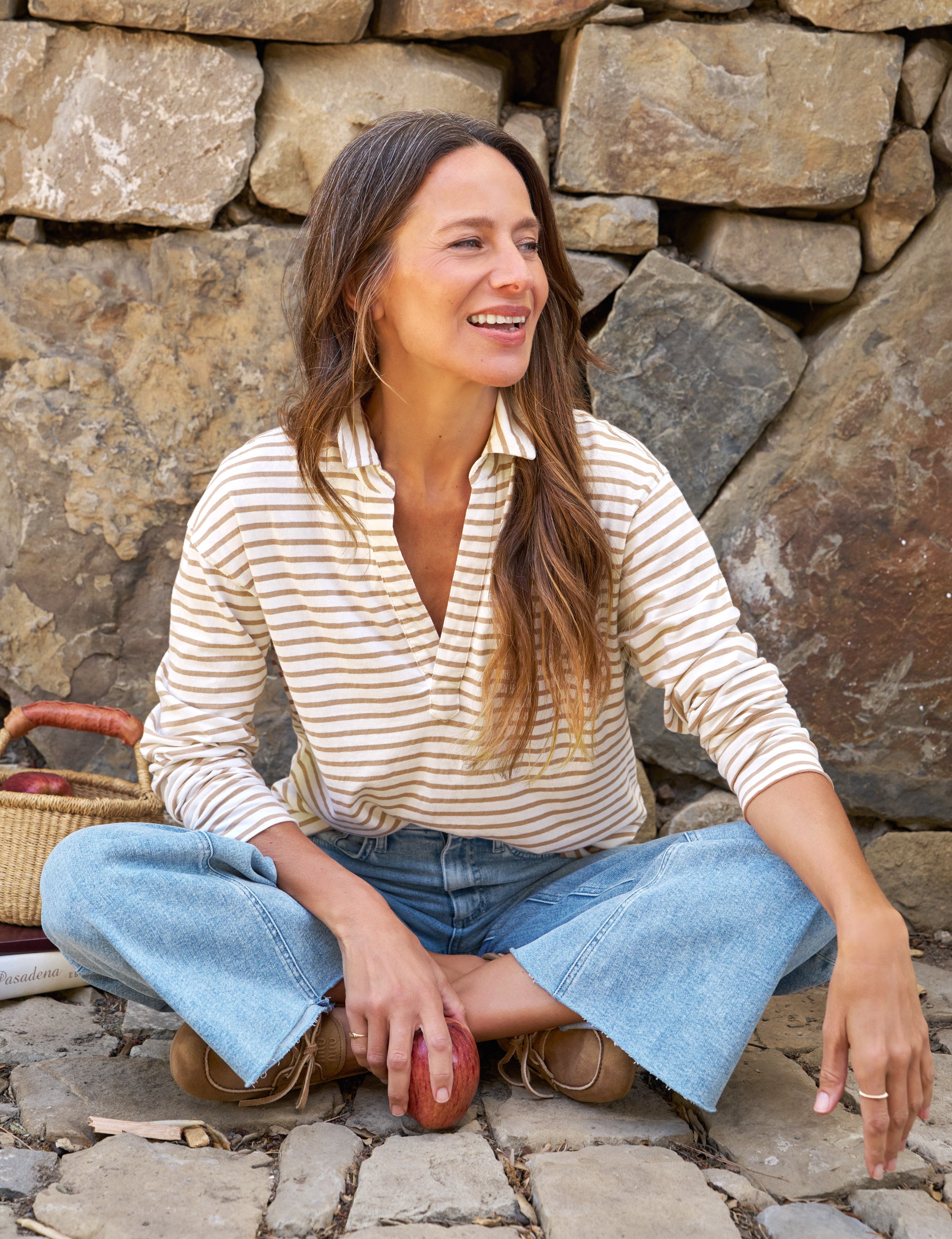 Woman sitting on a stone path with a stone wall background