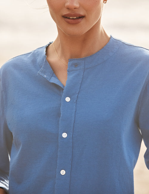 Person wearing a blue button-up shirt with a blurred background, alternate view