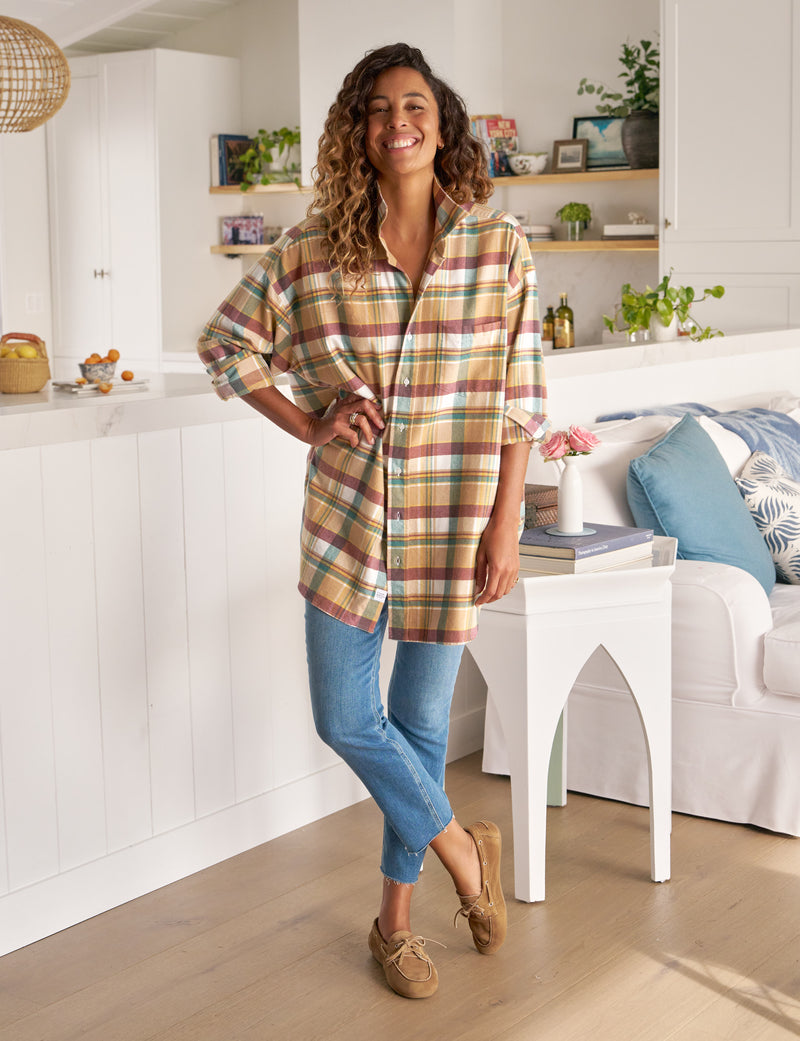 Woman wearing a plaid shirt and jeans standing in a modern kitchen.