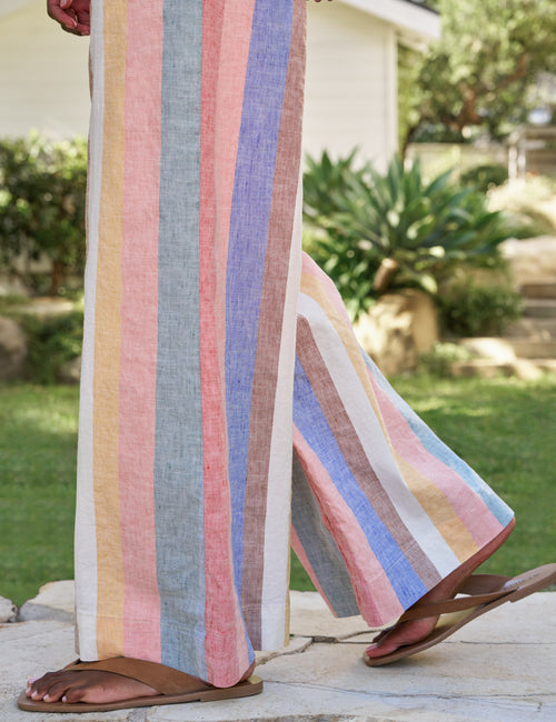 Person wearing a colorful striped dress standing outdoors with greenery in the background, view 3