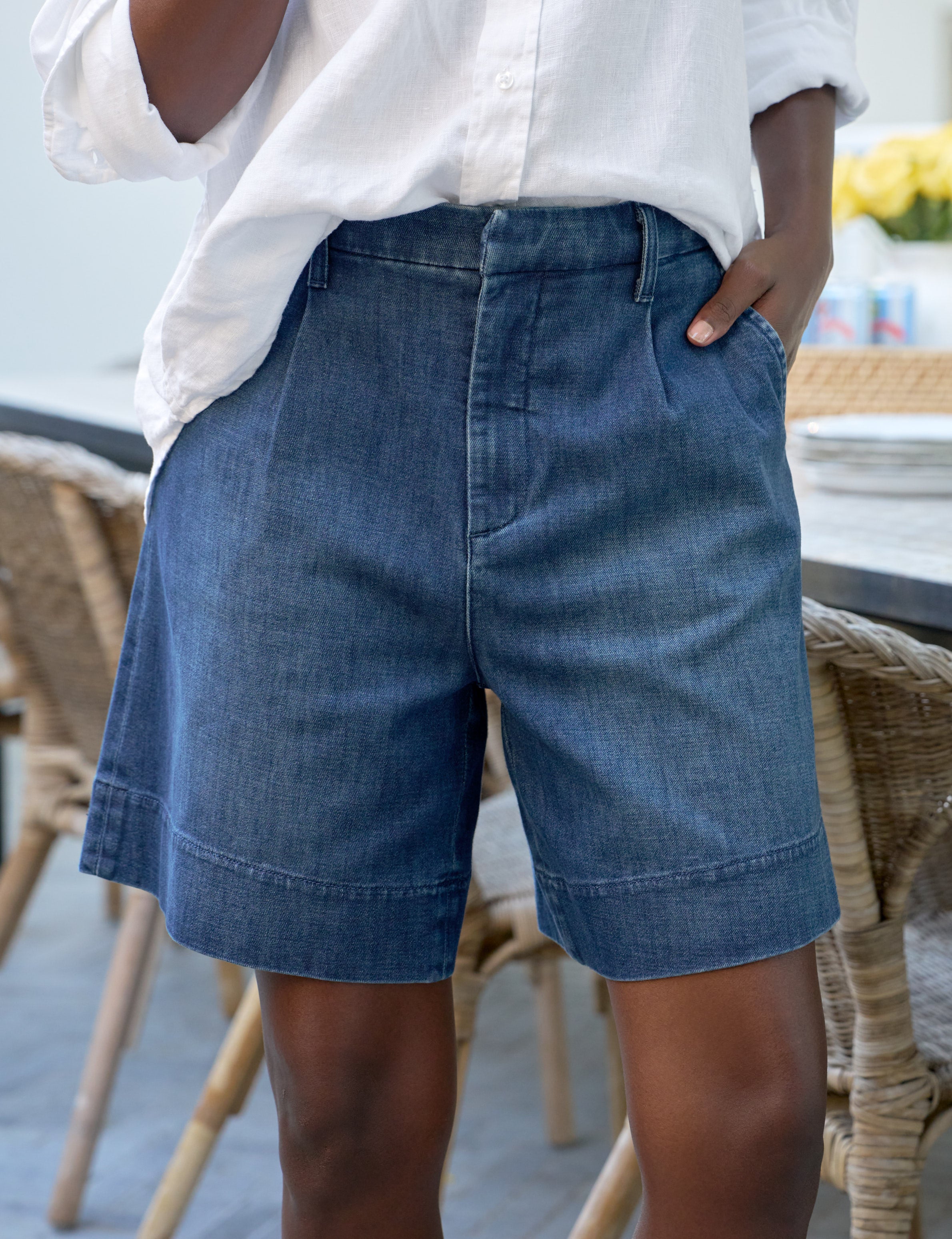Person wearing blue denim shorts and a white shirt in an outdoor setting.
