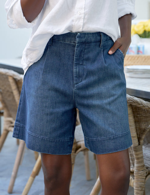 Person wearing blue denim shorts and a white shirt in an outdoor setting., front view