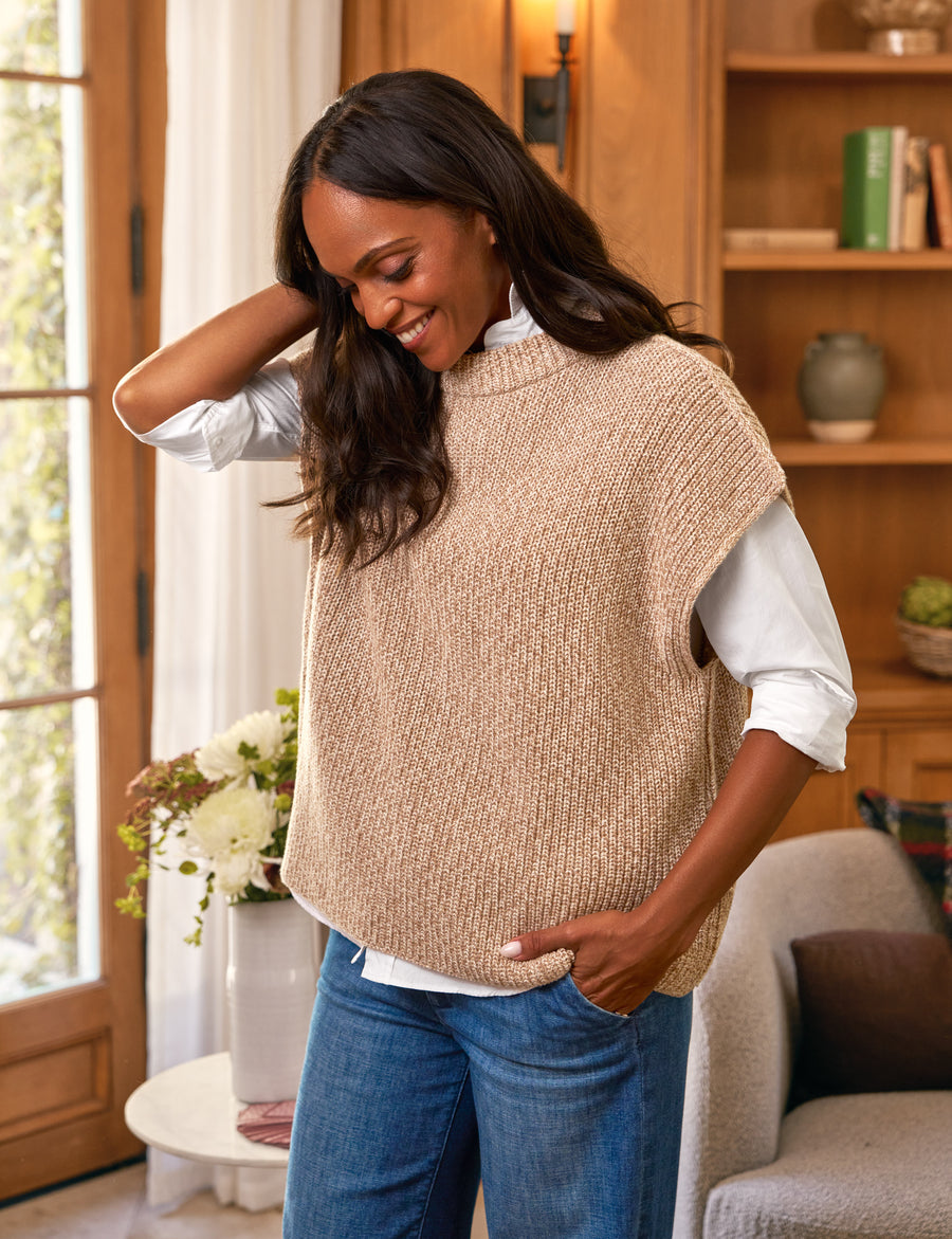 Woman wearing a beige knitted vest in a home setting
