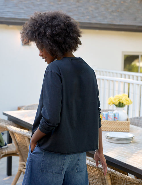 Woman standing outdoors by a dining table with a house in the background, alternate view
