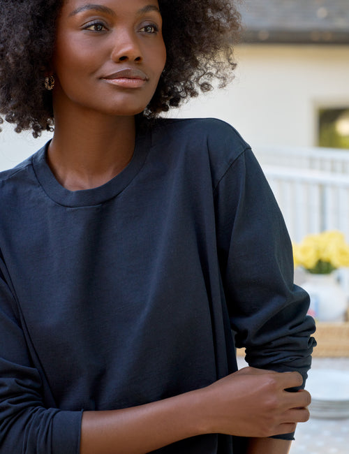 Woman wearing a dark blue long-sleeve shirt outdoors, view 3
