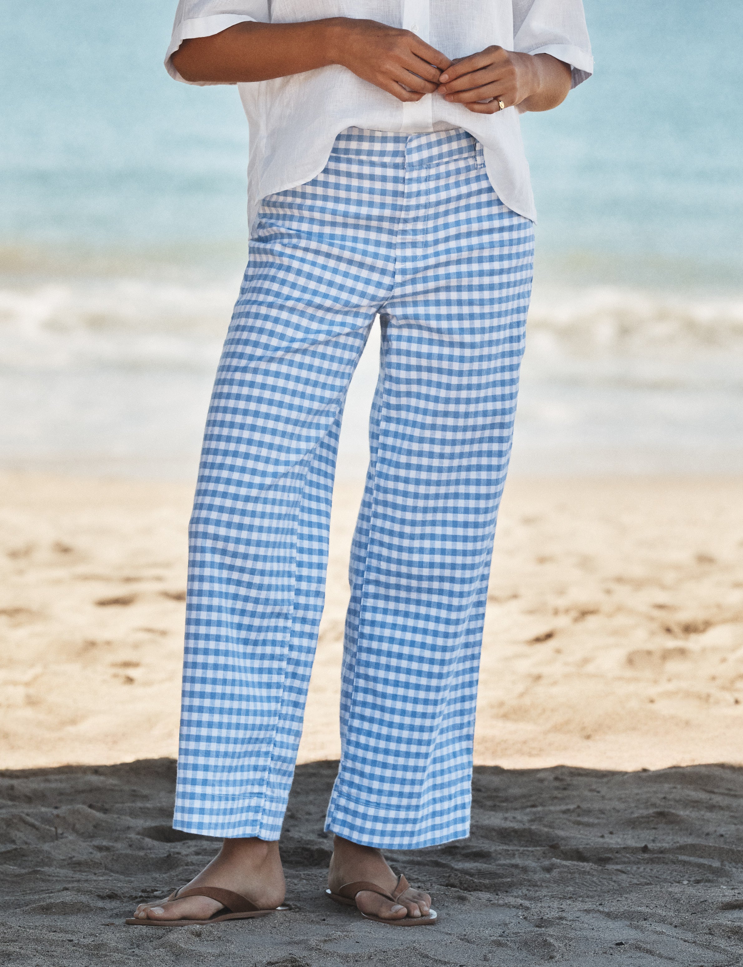 Person wearing blue checkered pants on a beach, front view