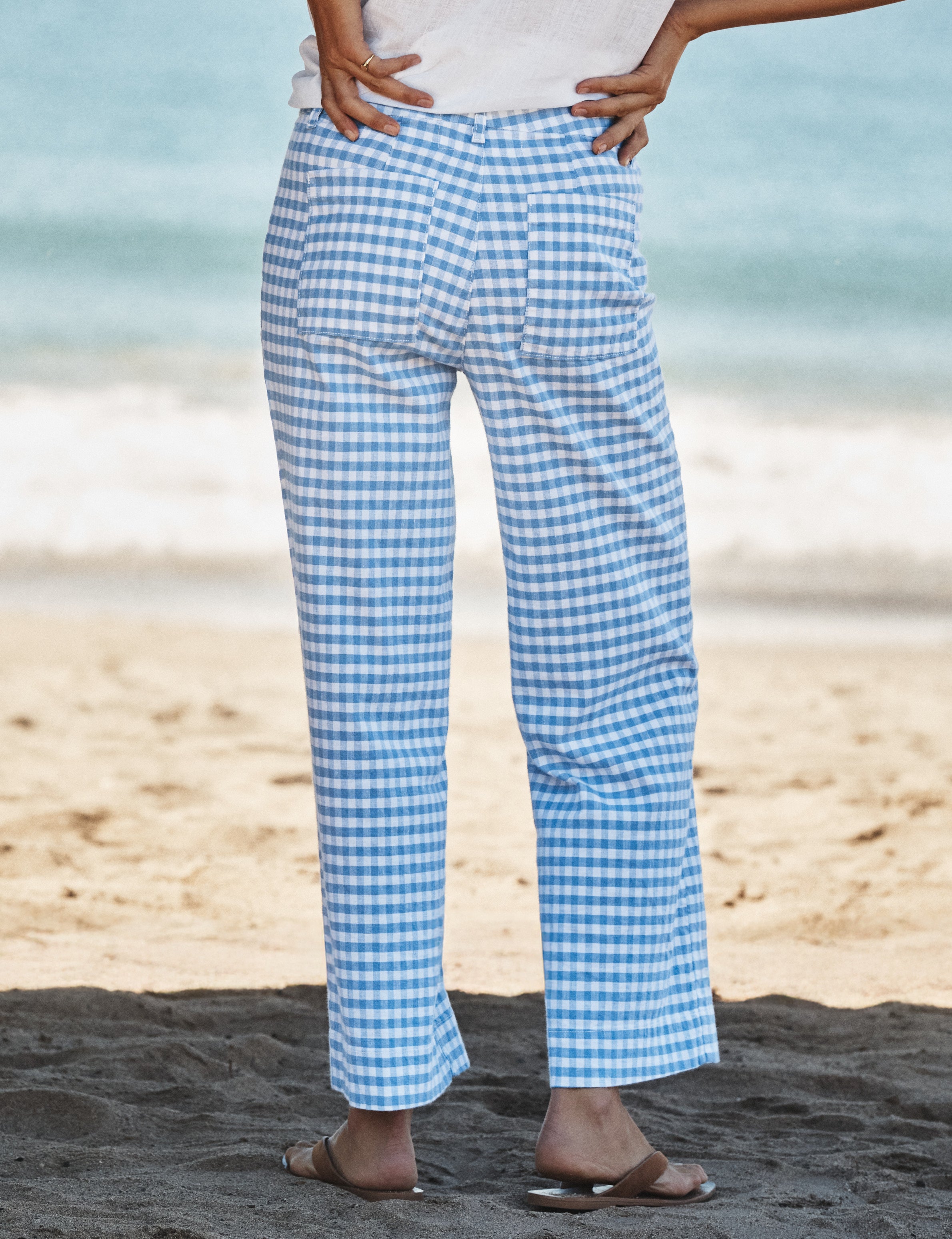 Person wearing blue and white checkered pants on a beach., alternate view