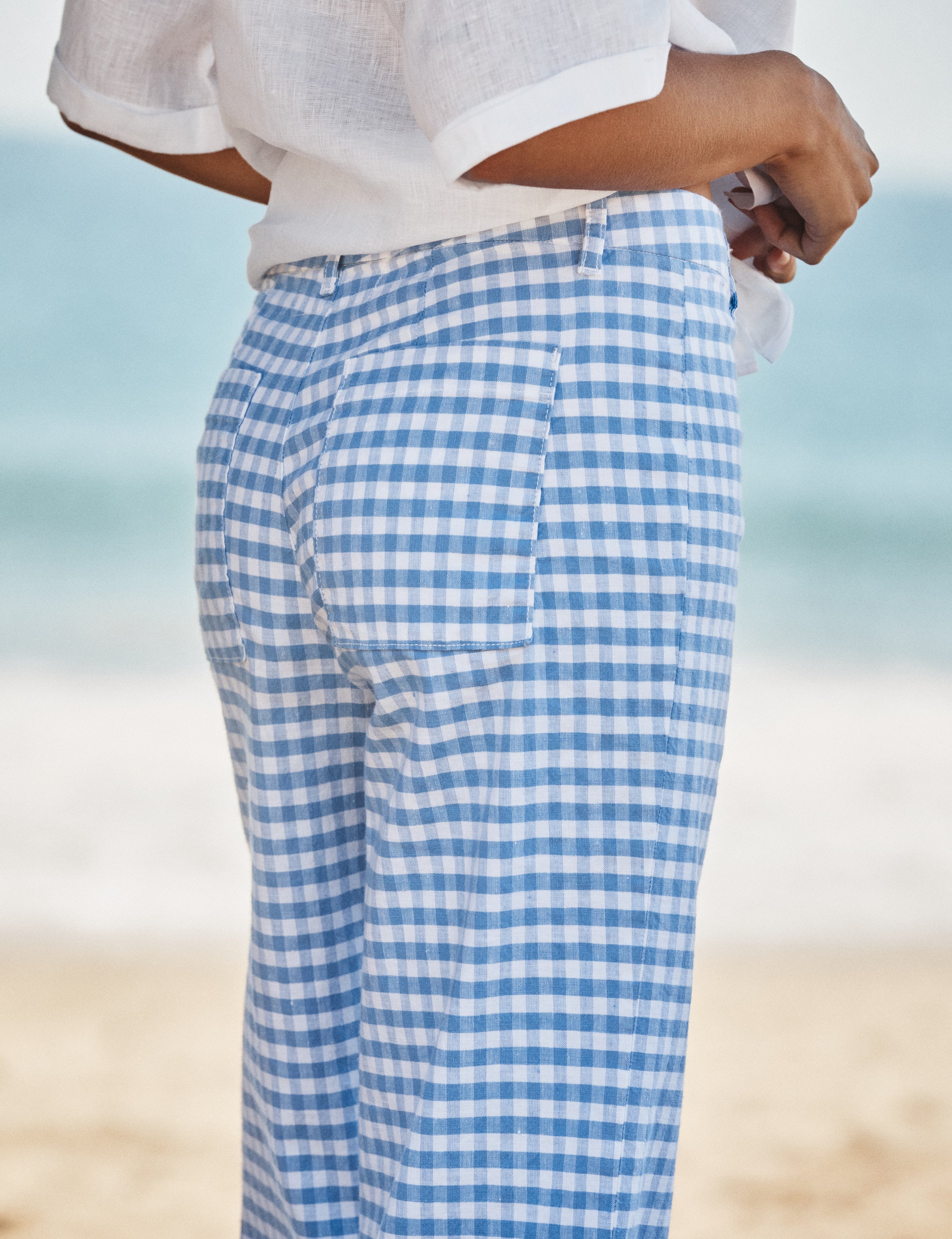 Person wearing blue and white checkered pants on a beach., view 3