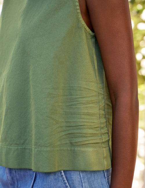 Green sleeveless top worn by a person with a blurred natural background, view 3