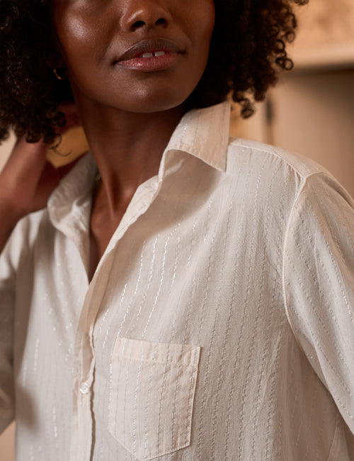 A close-up of a model wearing a cream-colored, textured long-sleeve button-up shirt with a chest pocket., view 3