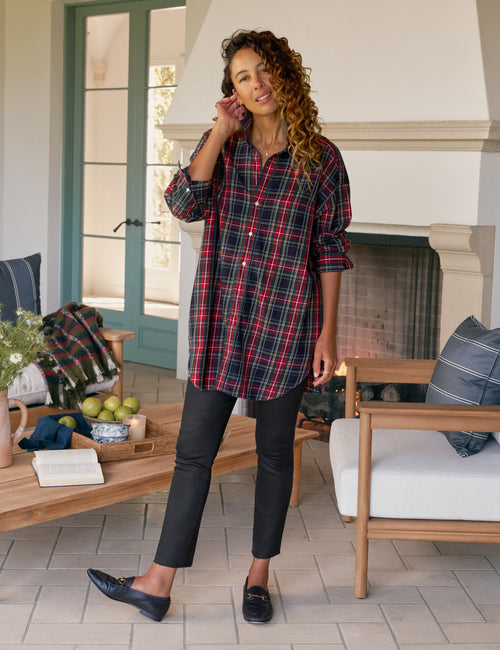 Woman in plaid shirt and black pants standing in a cozy living room., view 4