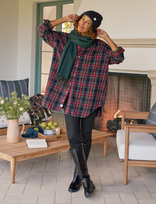 Person wearing a plaid shirt, black leggings, and black boots in an outdoor living space., view 3