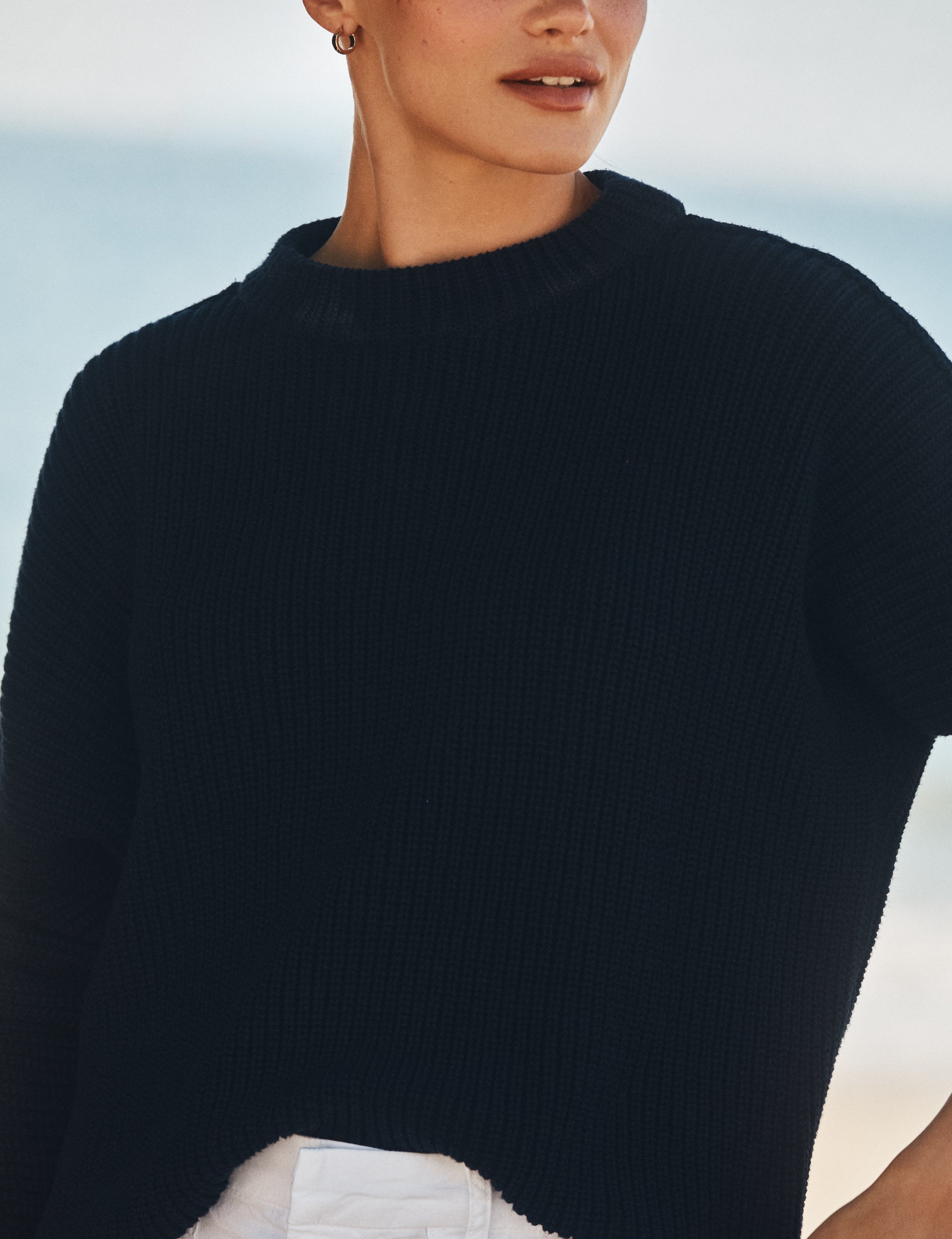 Person wearing a dark blue sweater with a blurred background, view 3