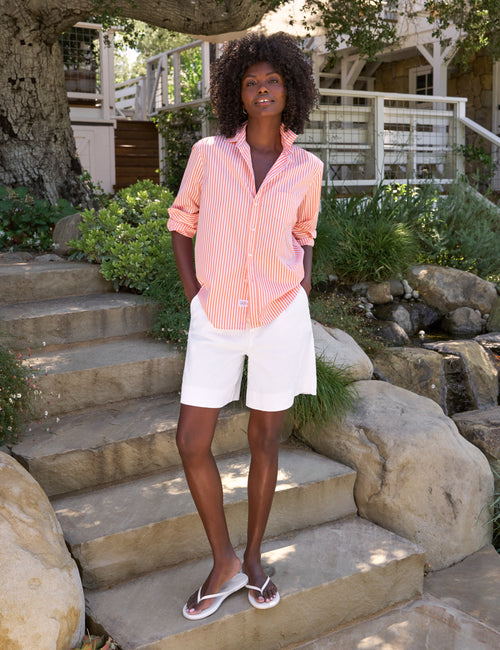 Woman in a striped shirt and white shorts standing on stone steps outdoors., view 5